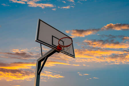 Basketball board with basket hoop against sunset sky. Sport, recreation.