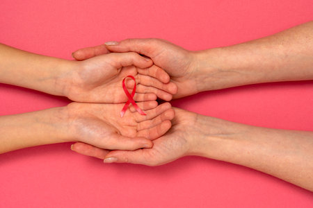 Adult and child hands holding pink ribbon. Breast cancer awareness, abdominal cancer awareness and October Pink day background , world cancer day.の写真素材