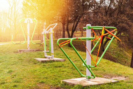 Empty outdoor fitness equipment wrapped with warning tape. Sports are prohibited, sports area closure Covid-19の写真素材