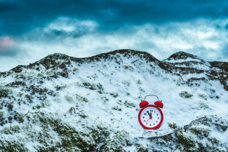 Alarm clock on a rock covered by snow.