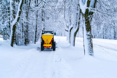 Tractor with mounted salt spreader, road maintenance - winter gritter vehicle. Tractor de-icing...