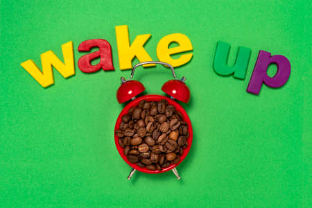 Good morning coffee and alarm clock concept. Coffee beans in retro alarm clock with word wake upの写真素材