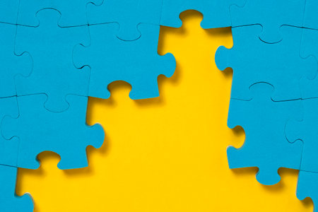 Unfinished blue jigsaw puzzle on yellow background with copy space. Business strategy teamwork and problem solving concept. Teamwork is collaborative effort of team to achieve goal or complete task.の写真素材