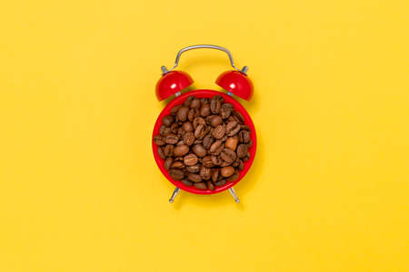 Morning coffee and alarm clock concept. Coffee beans on alarm clock face.の写真素材