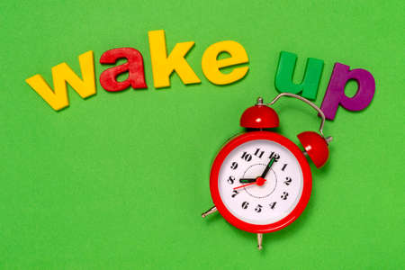 Alarm 8 o' Clock and wake up concept. Alarm clock on the green background with words Wake Up.