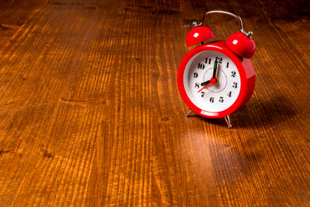 Old fashioned red alarm clock on the old wooden table background
