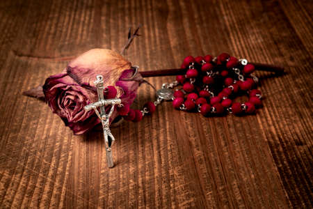 Catholic rosary and wilted rose, close-up view. Faith and hope concept.の写真素材