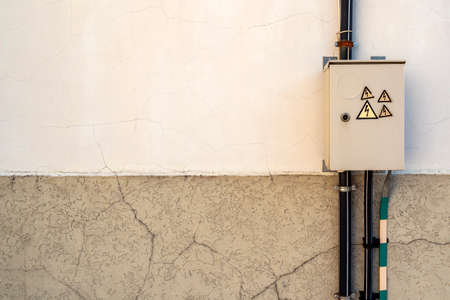 Locked electric panel with hazard sign on the grey wall of transformer substation