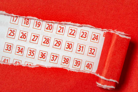 Red paper torn to reveal lottery ticket numbers. Conceptual image.の写真素材