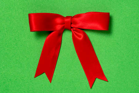 Single red ribbon satin gift bow on the green backgroundの写真素材