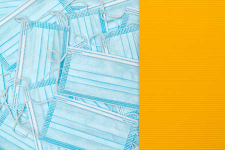 Medical face mask for against the corona virus, covid-19. Surgical mask with rubber ear straps. Typical 3-ply surgical mask to cover the mouth and nose. Procedure mask from bacteria. A lot of medical protective masks with yellow banner for text.の写真素材