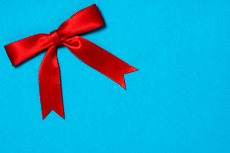 Red ribbon satin gift bow on the blue background. Copy space.の写真素材