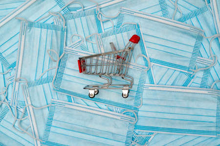 Supermarket basket on the protective medical masks. Coronavirus shopping concept.
