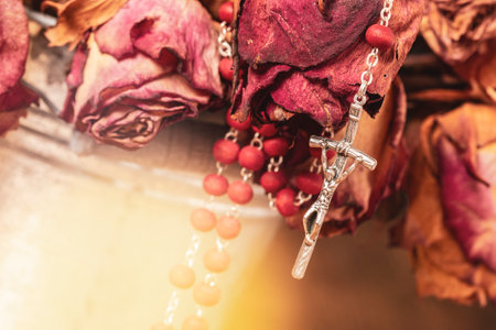 Metal bucket with wilted roses and catholic rosary. Religion concept.