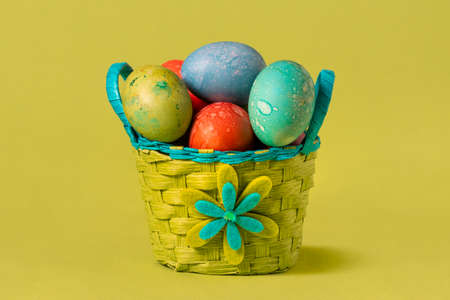 Colorful Easter eggs in handmade basket on the green background