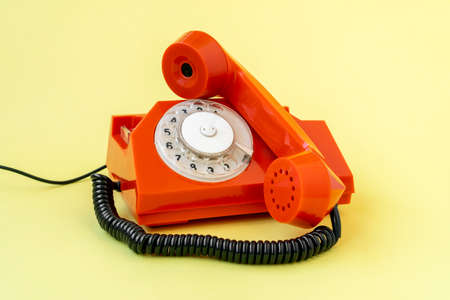 Retro orange telephone on yellow background. Communication concept.の写真素材