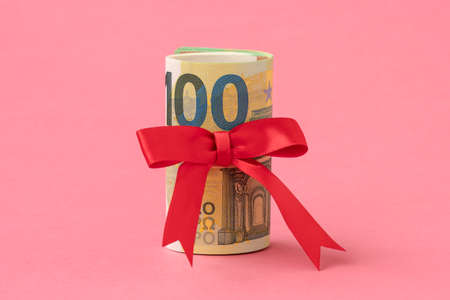 Money roll with decorative bow on the pink background. Money gift. Money bonus.の写真素材