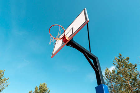 Broken metal net on basketball basket outside on blue sky backgroundの写真素材
