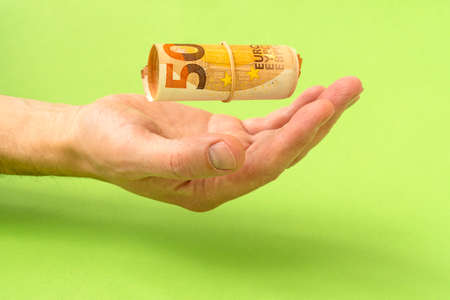 Hand catching a falling Euro money rollの写真素材
