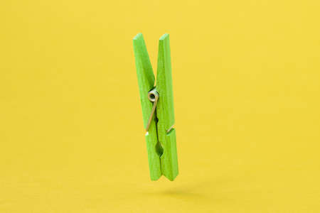 Green wooden clothes peg over yellow backgroundの写真素材