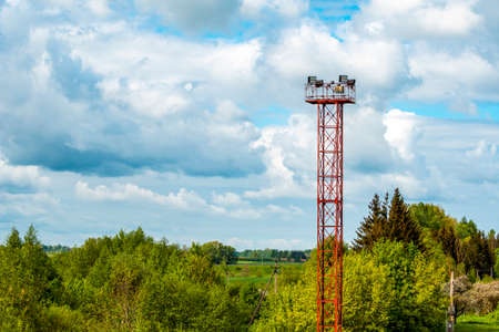 Tall tower with spot lights or lamps for railroad against  sky background with white cloudsの写真素材