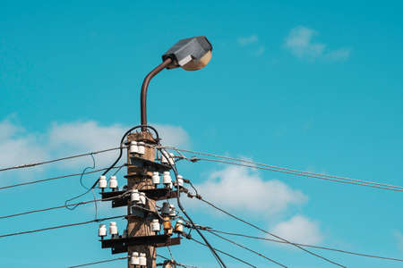 Concrete pylon with wires and street lamp on the sky background