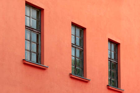 A row of old windows on the red concrete wallの写真素材