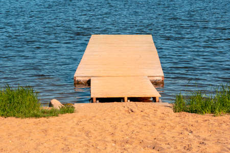 Wooden pier (bridge) extents from beach to turquoise wave sea
