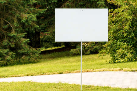 Empty white sign on the street with green nature on backgroundの写真素材
