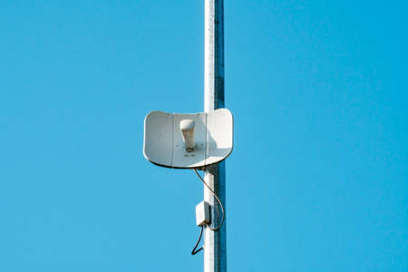 Wireless internet access point antenna on a street pole over a blue sky background