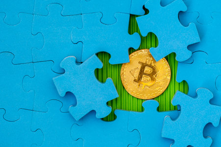 Blue jigsaw puzzle with golden bitcoin underneathの写真素材
