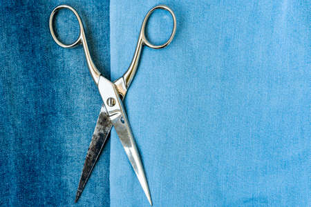 Old metal tailor scissors on blue jeans textureの写真素材