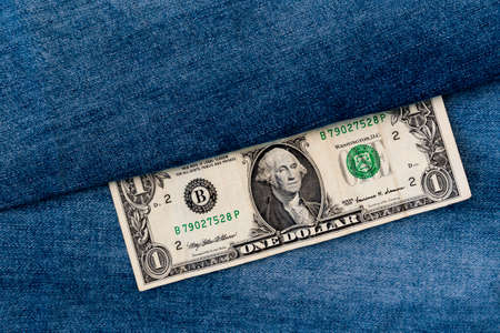 Money and fashion. One dollar bill on a denim jeans background.  Concept of earning and saving money. American money.の写真素材