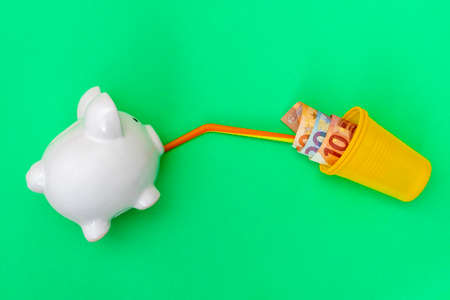 Piggy bank drinking coctail made from money. Business concept.の写真素材