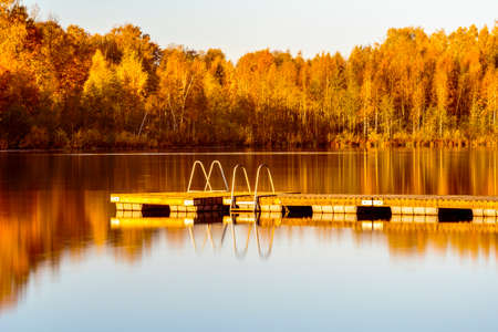 Wooden bridge with fall colour reflected in the still watersの写真素材