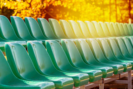 Rows of green plastic seats on the school stadium during fall seasonの写真素材