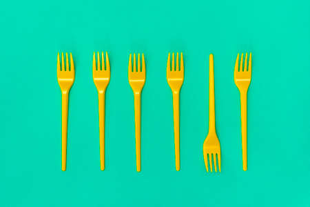 Yellow disposable forks lying on the blue background. Top view.