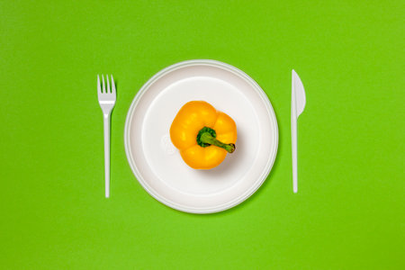 Yellow bell pepper on a white plate, fork and knife, dieting, healthy food concept. Food creative...