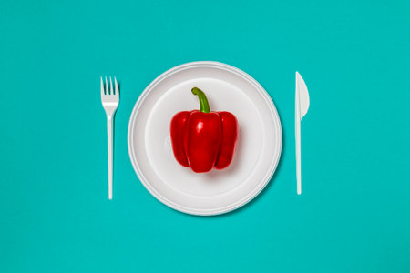 Red bell pepper on a white plate, fork and knife, dieting, healthy food concept. Food creative concept. Top view Pink Background Flat Lay with copy space.の写真素材