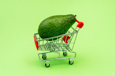 Avocado in shopping grocery cart. Shopping at the supermarket. Fresh vegetables and fruits.の写真素材