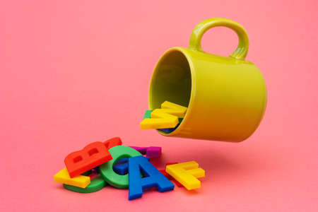 Plastic color letters spill out of ceramic cup