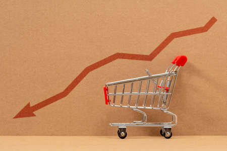Empty grocery cart with the indicator of a falling economy. Concept of the economic crisis. Inflation. Food shortages, logistics problems.の写真素材