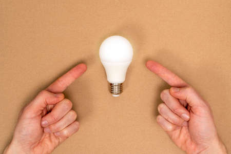 Hands pointing to glowing light bulb. Business start up or goal to success.