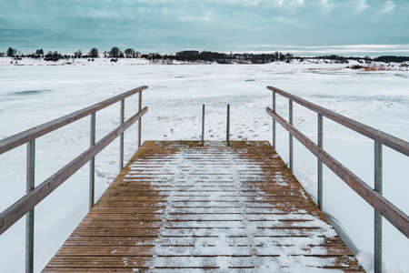 Wooden pier on lake with fresh snow.Frosty calm landscape. Natural tranquil atmosphere for relaxation.の写真素材