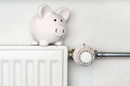 Piggy bank on central heating radiator. Concept image for saving money on heating.の写真素材