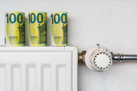 Heating radiator with thermostat and money, expensive heating costs conceptの写真素材