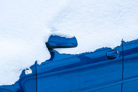 Side of a snow covered car in a cold winter morning