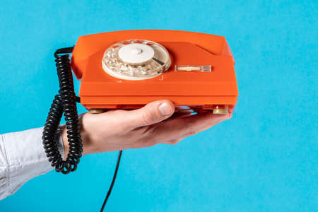 Hand with old rotary telephone over blue background.Communication concept.の写真素材