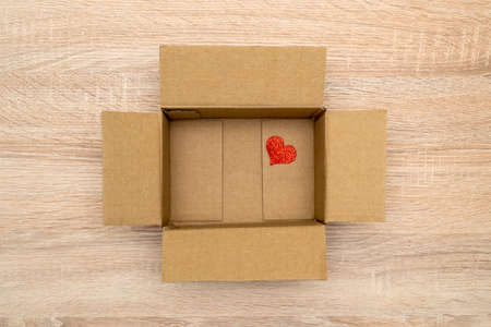 Small red heart on the bottom of cardboard box. Heart In The Open Cardboard Box.の写真素材