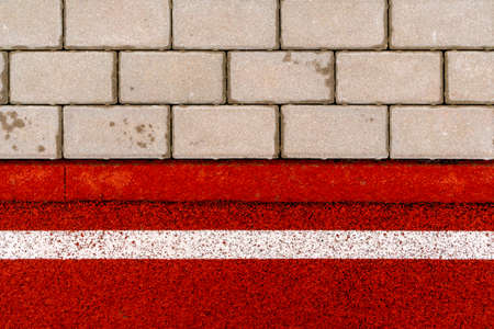 Close-up shot of red soft rubber matt jogging track and tile pavement